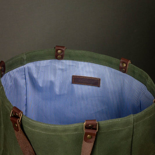 Green bag with brown straps and blue interior on a dark background
