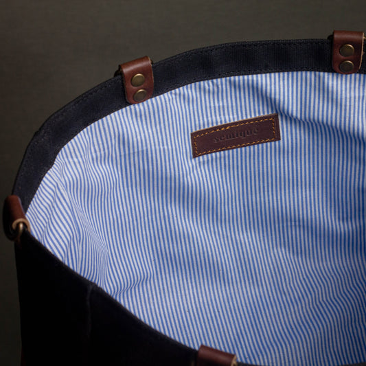 Close-up of a blue and white striped fabric with a brown leather tag on a dark background