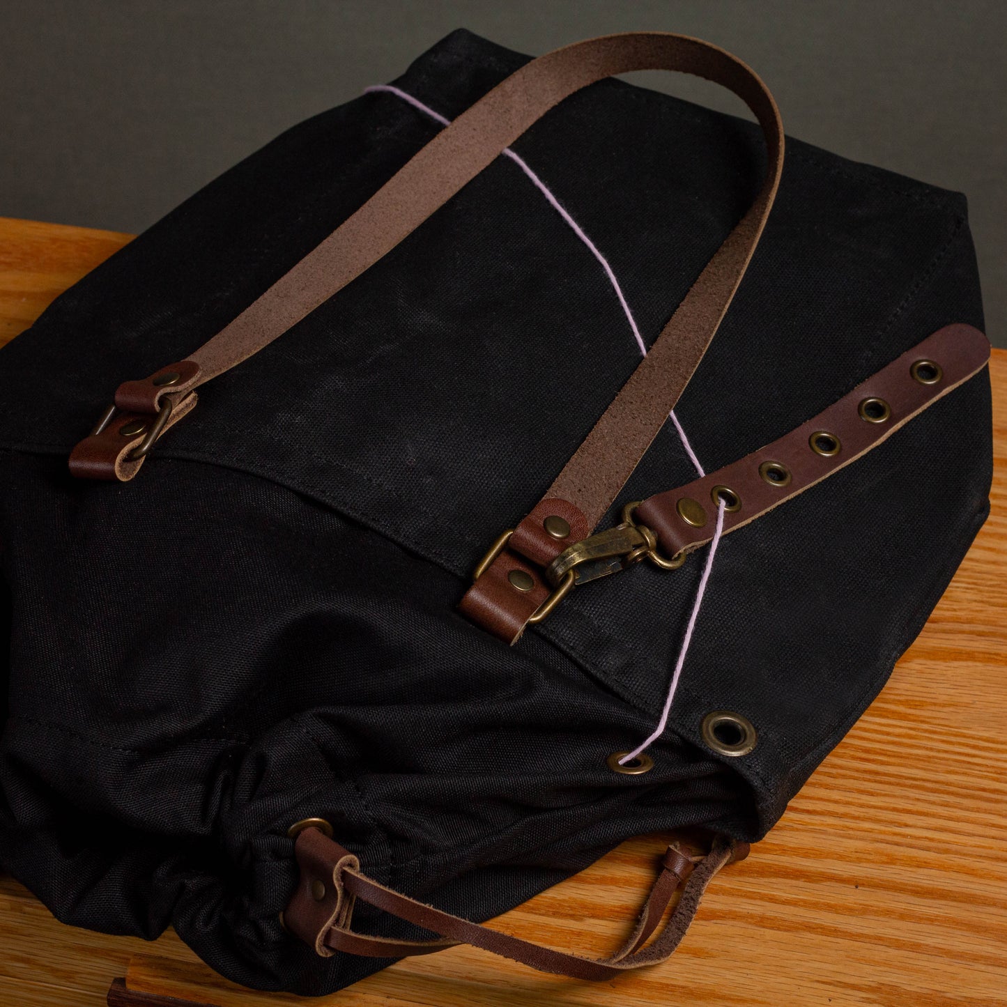 Black canvas bag with brown leather straps on a wooden surface
