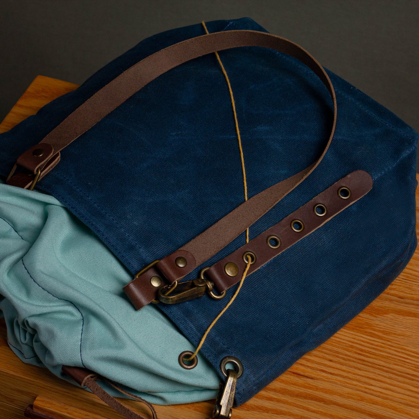 Blue bag with brown leather straps on a wooden surface