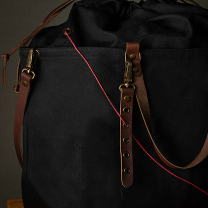 Black bag with brown leather straps on a dark background
