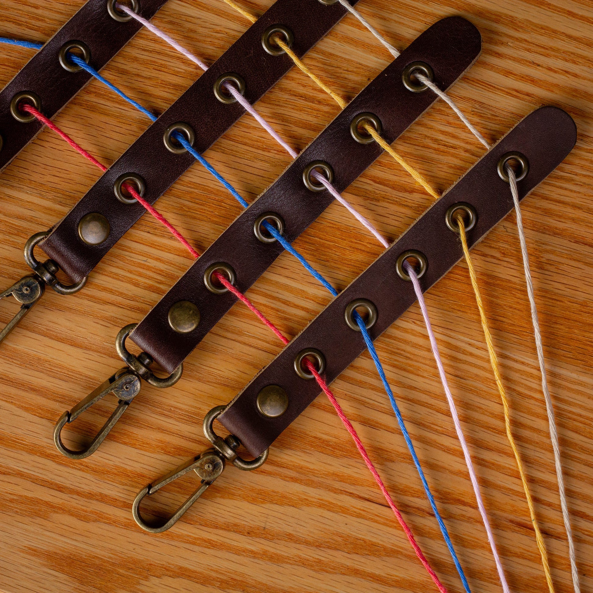 Brown leather keychain with colorful strings on a wooden surface