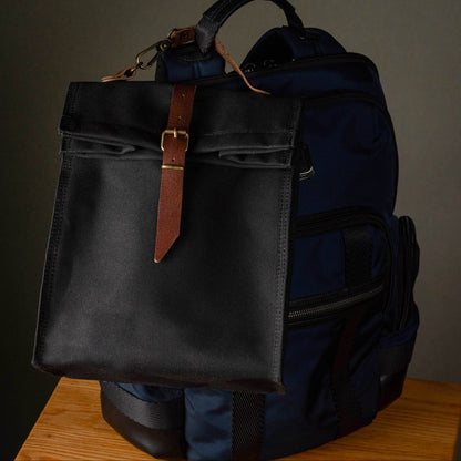 Black and blue backpack with leather strap on a wooden surface