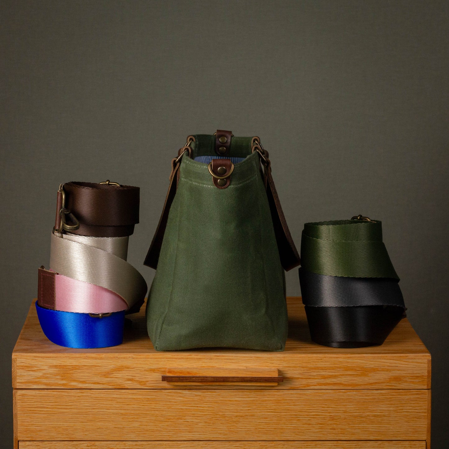 Three colorful leather bags on a wooden surface with a gray background