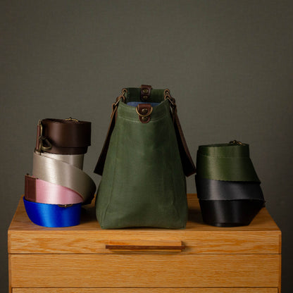 Three colorful leather bags on a wooden surface with a gray background