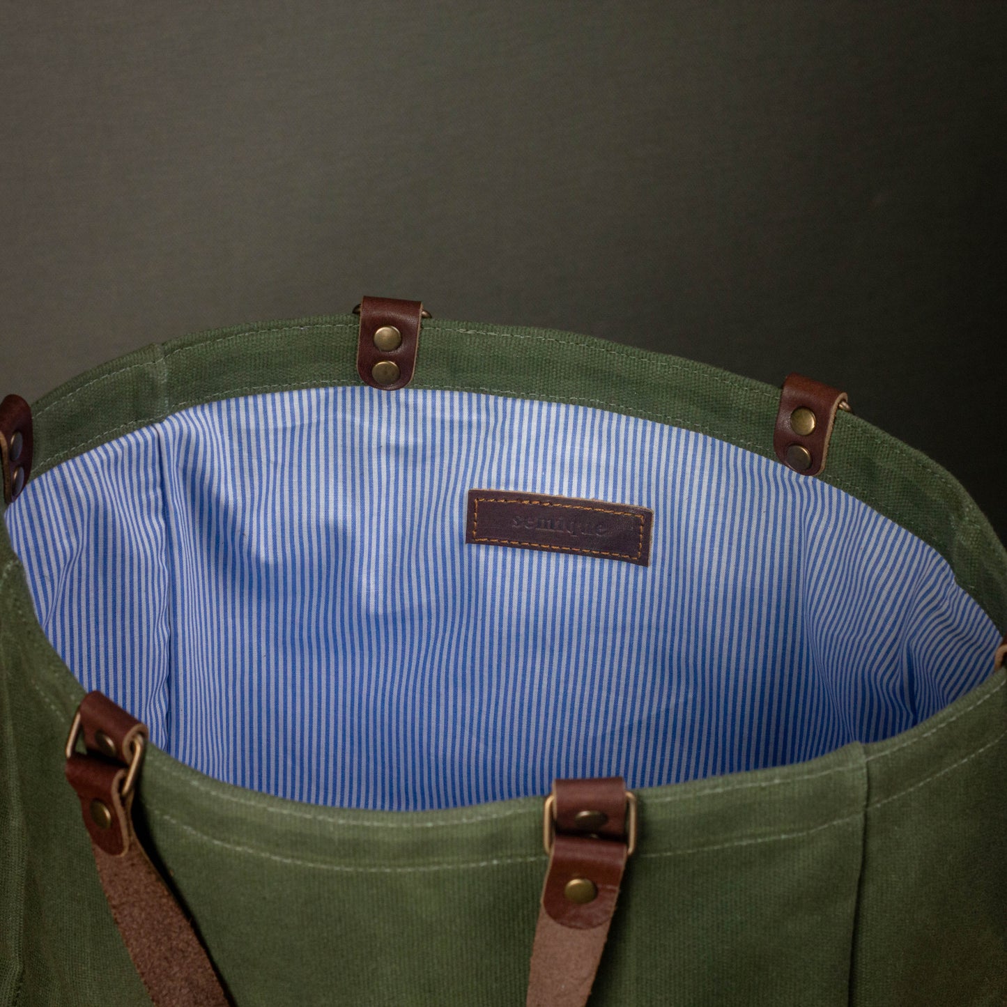 Green bag with brown straps and blue interior on a dark background