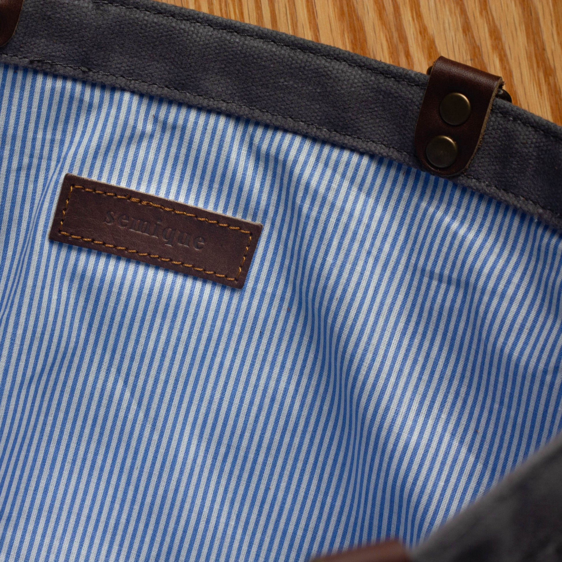Close-up of a blue and white striped fabric with a leather label and button.