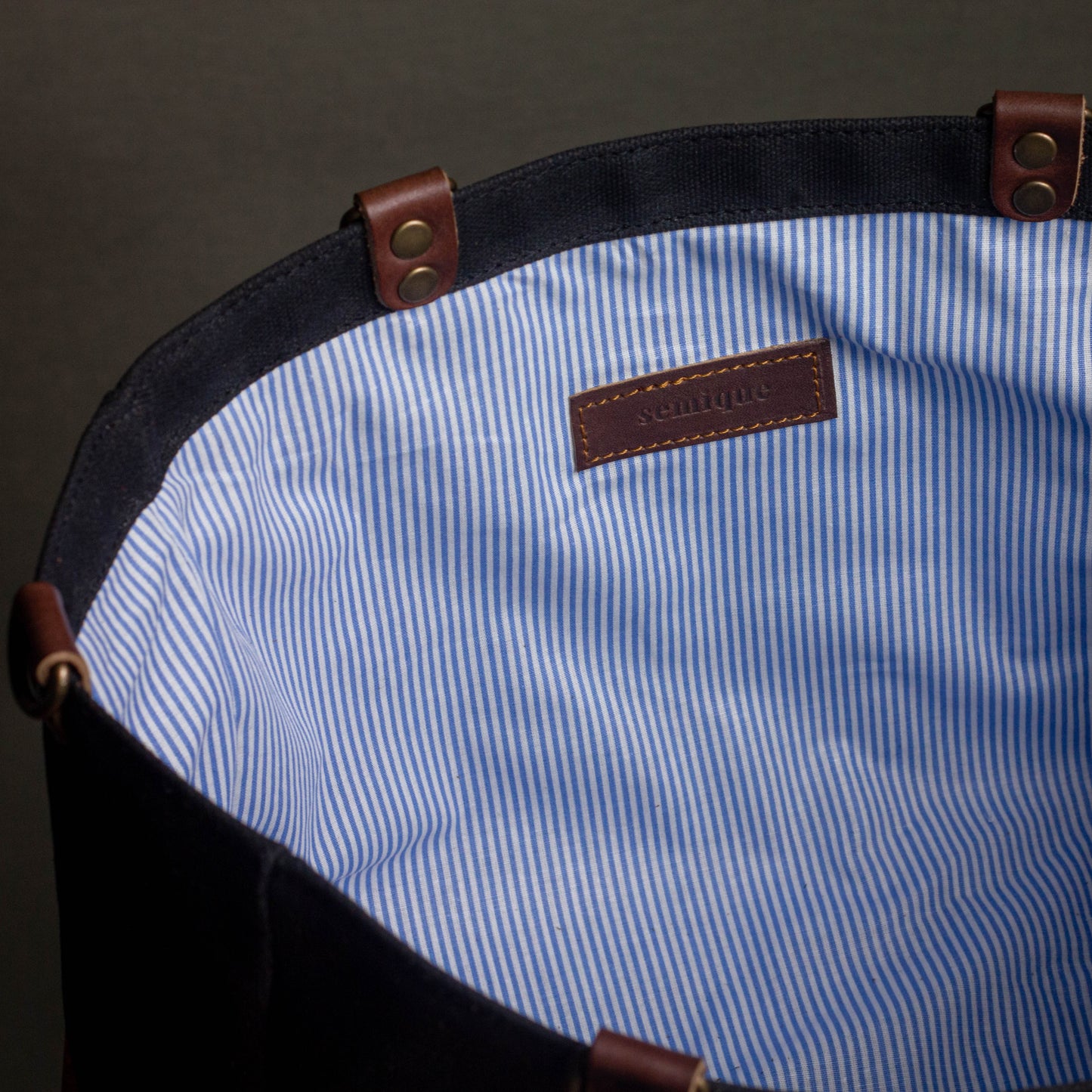 Close-up of a blue and white striped fabric with a brown leather tag on a dark background