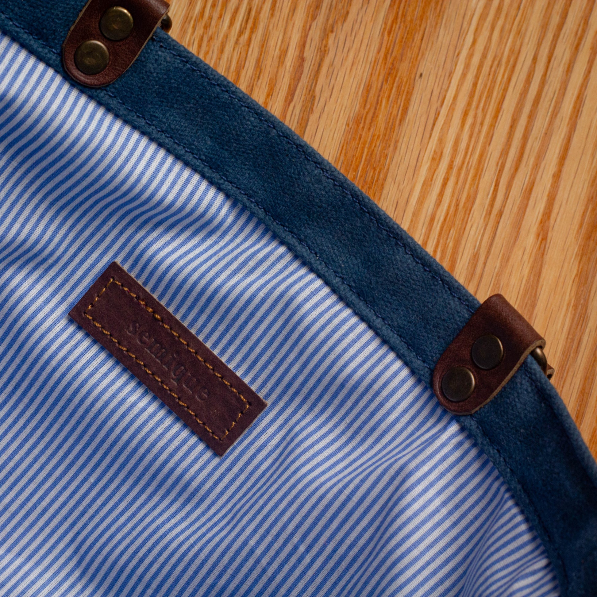 Close-up of a blue and white striped fabric with brown leather straps on a wooden surface